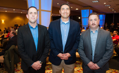 Three men stand in front of a crowd at the awards for moving services event in Fort Worth, TX